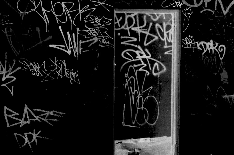 This is a photo of an open door in an abandoned warehouse that has graffiti scrawl on the walls.